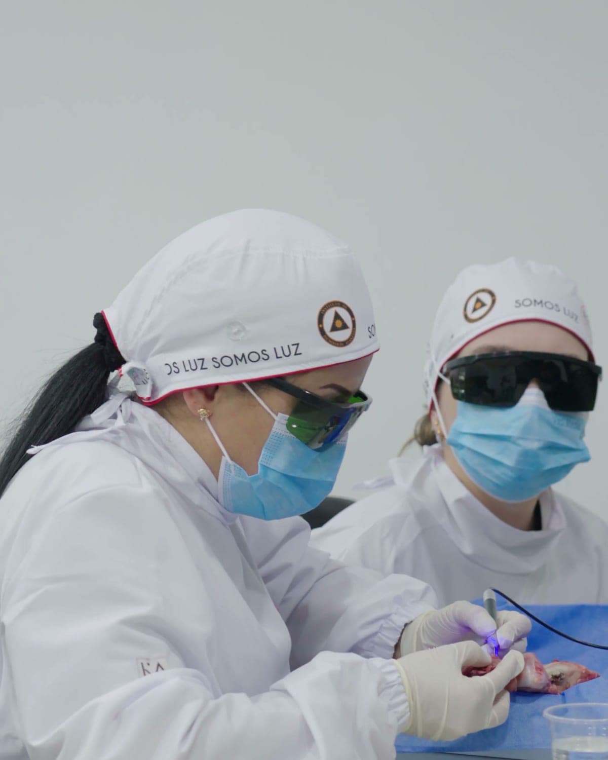 Dos participantes con gafas de protección practican con un láser odontológico